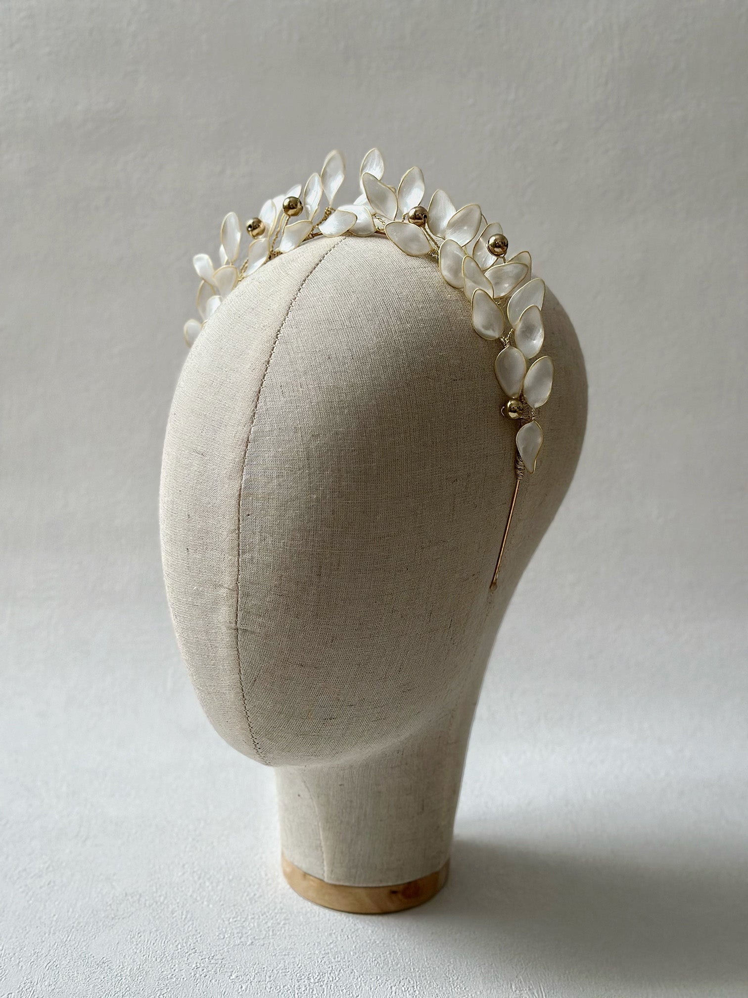 The Olea Tiara, with its epoxy-crafted, pearly white leaves resembling an olive branch, combines timeless elegance with modern aesthetics. Golden bead accents enhance its ethereal glow, offering a secure, graceful fit for bridal or sophisticated wear. A symbol of peace in a luxurious headpiece.